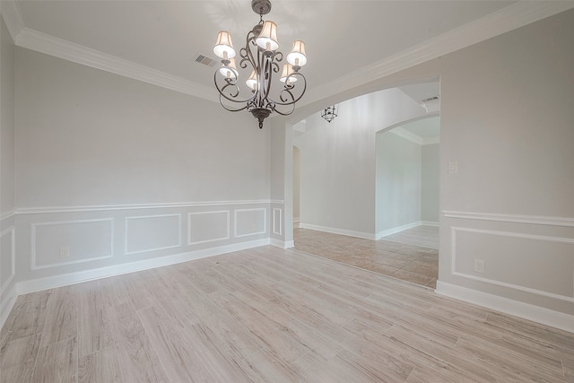 spare room featuring an inviting chandelier, ornamental molding, and light wood-type flooring