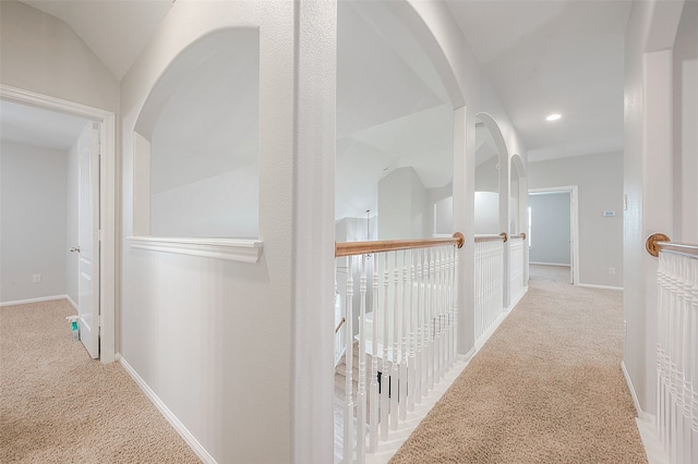 hallway with light colored carpet and vaulted ceiling