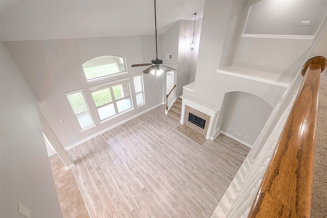 unfurnished living room featuring high vaulted ceiling, ceiling fan, light wood-type flooring, and a fireplace