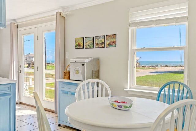 tiled dining space featuring a healthy amount of sunlight, ornamental molding, and a water view