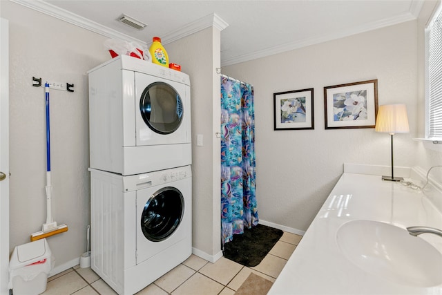 laundry area with plenty of natural light, ornamental molding, stacked washing maching and dryer, sink, and light tile floors