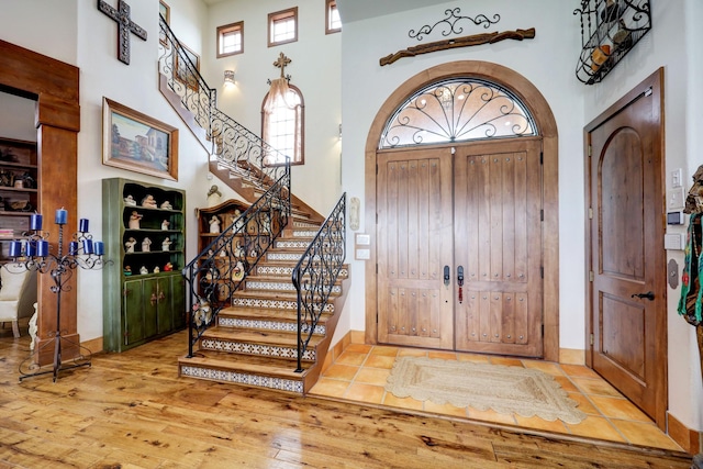 foyer entrance with a towering ceiling and light hardwood / wood-style flooring