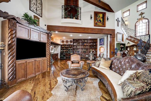 living room featuring a high ceiling, light hardwood / wood-style floors, and beamed ceiling