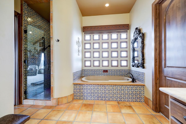 bathroom with tiled tub and tile patterned floors