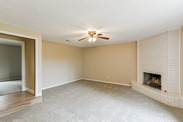 unfurnished living room with a fireplace, a textured ceiling, carpet, and ceiling fan