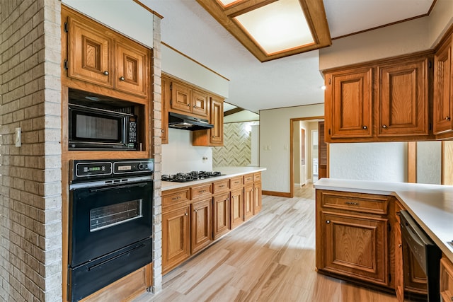 kitchen with tasteful backsplash, black appliances, and light hardwood / wood-style flooring