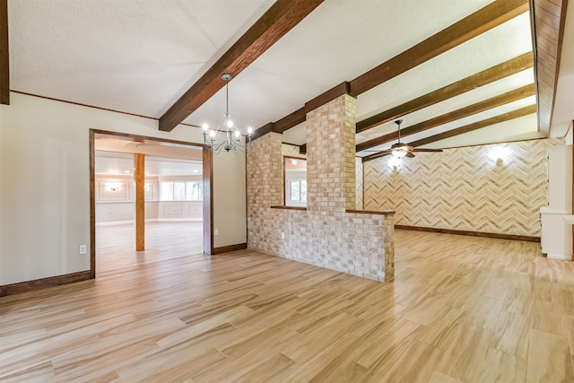 unfurnished living room featuring vaulted ceiling with beams, light hardwood / wood-style flooring, ornate columns, and ceiling fan with notable chandelier