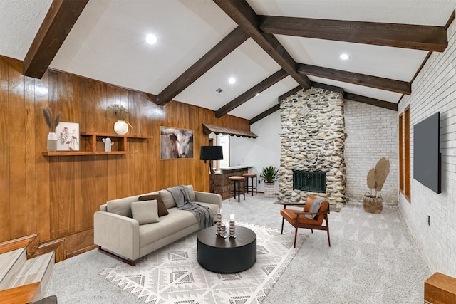 carpeted living room featuring a stone fireplace, lofted ceiling with beams, and wooden walls