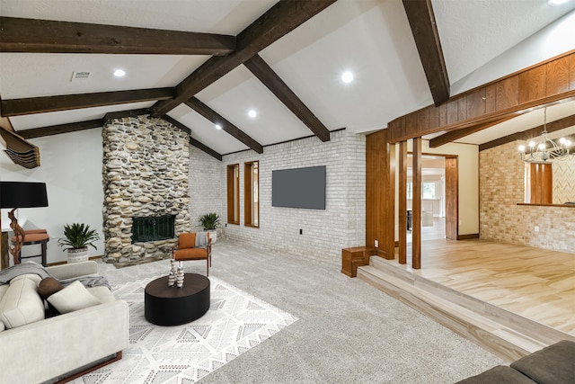 living room featuring vaulted ceiling with beams, light hardwood / wood-style flooring, a fireplace, a notable chandelier, and brick wall