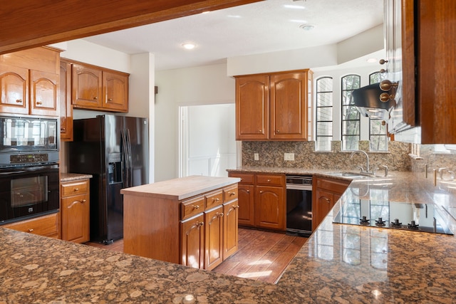 kitchen featuring dark hardwood / wood-style floors, sink, dark stone countertops, black appliances, and tasteful backsplash