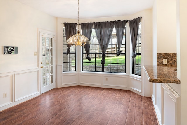 unfurnished dining area featuring a chandelier and dark hardwood / wood-style flooring