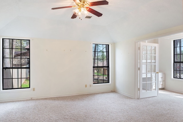 carpeted spare room featuring plenty of natural light, ceiling fan, and vaulted ceiling