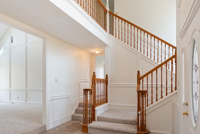 stairway with light colored carpet and a high ceiling