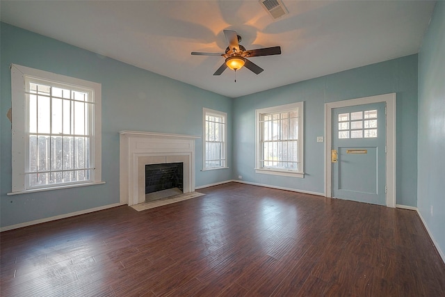 unfurnished living room with plenty of natural light, ceiling fan, and dark wood-type flooring