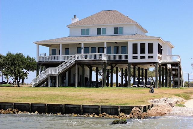 back of house with a lawn and a water view