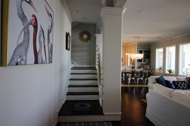 corridor with a notable chandelier, ornamental molding, dark hardwood / wood-style flooring, and decorative columns