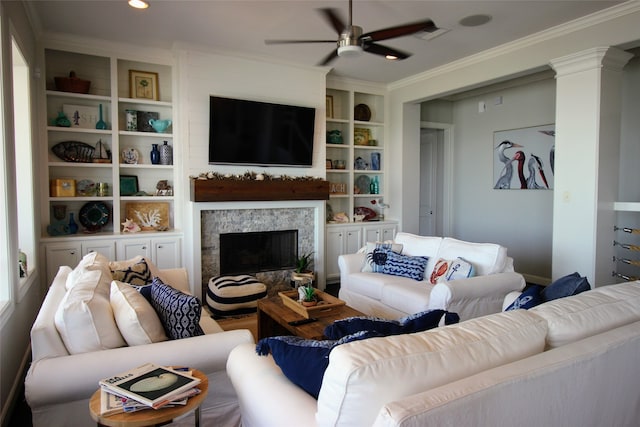 living room featuring built in features, ceiling fan, ornamental molding, and ornate columns