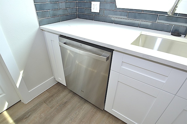 kitchen with backsplash, stainless steel dishwasher, sink, light hardwood / wood-style flooring, and white cabinetry