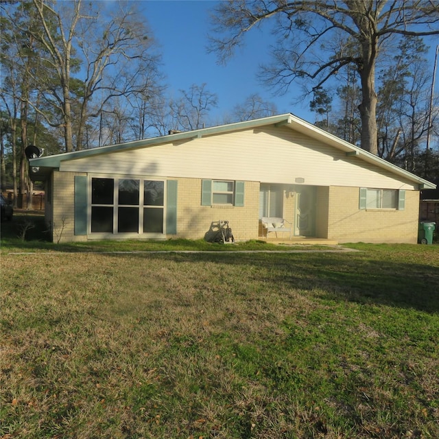 rear view of property featuring brick siding and a lawn