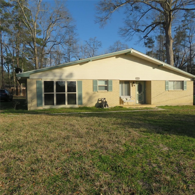 rear view of house featuring brick siding and a lawn