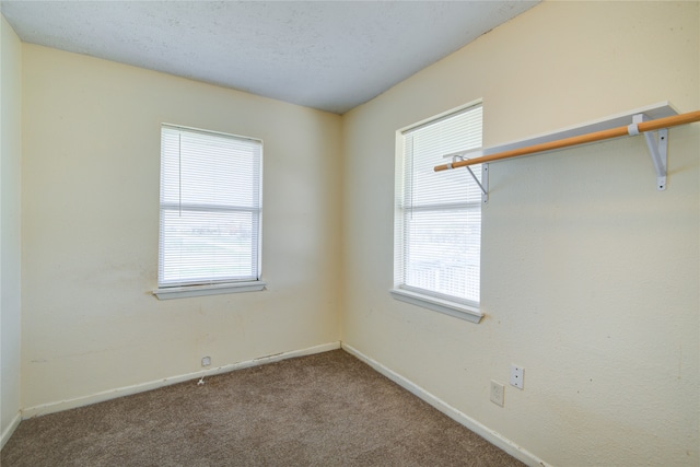 spare room featuring dark carpet and a textured ceiling