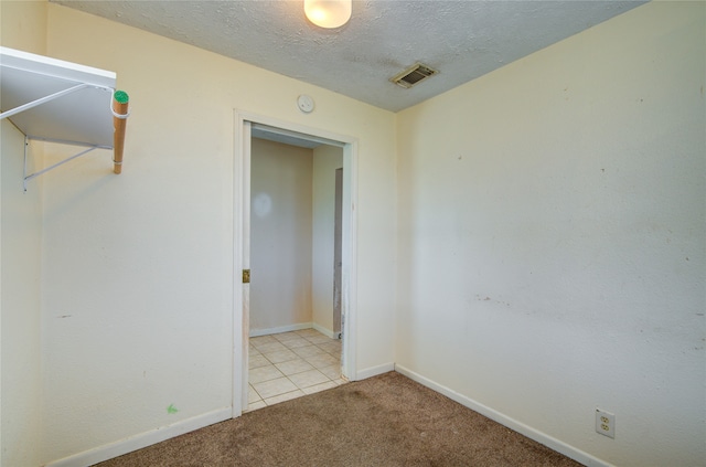 carpeted empty room with a textured ceiling