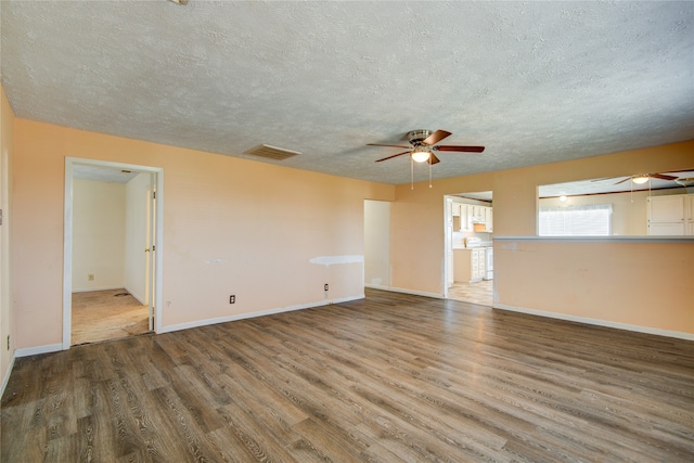 unfurnished room featuring ceiling fan, dark wood-type flooring, and a textured ceiling