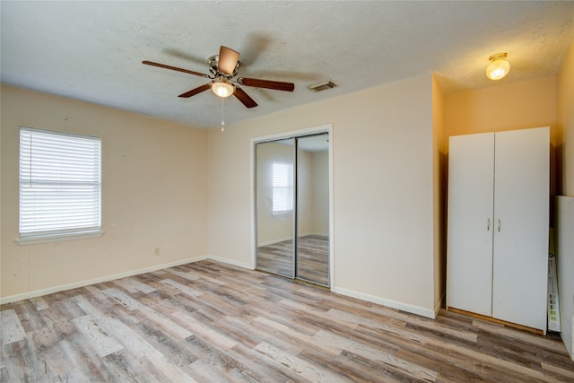 unfurnished bedroom with light hardwood / wood-style floors, a closet, ceiling fan, and multiple windows