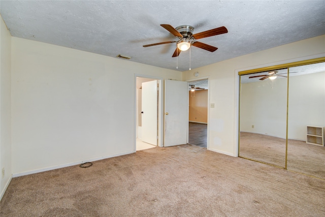 unfurnished bedroom featuring light colored carpet, a closet, ceiling fan, and a textured ceiling