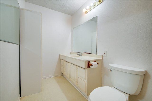 bathroom featuring toilet, vanity with extensive cabinet space, and a textured ceiling