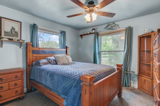 bedroom with ceiling fan, dark carpet, and multiple windows