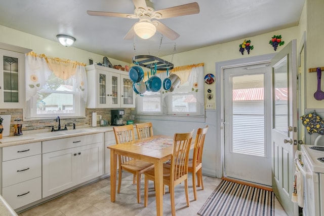 kitchen with sink, a wealth of natural light, white cabinetry, and backsplash