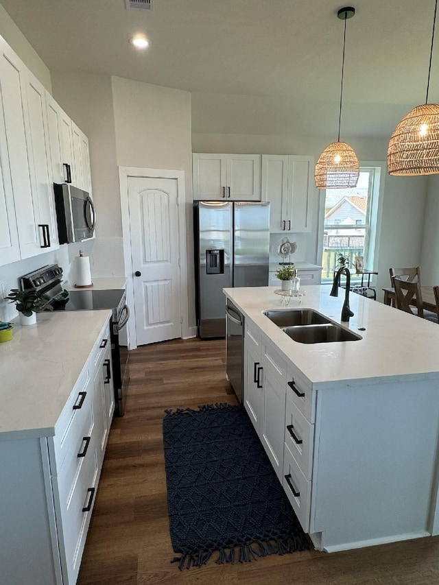 kitchen with sink, dark hardwood / wood-style floors, stainless steel appliances, and an island with sink