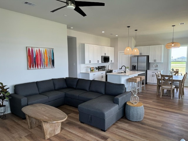 living room featuring ceiling fan, sink, and hardwood / wood-style flooring