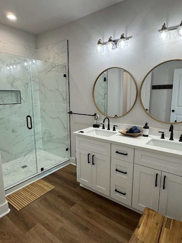 bathroom with dual vanity, a shower with door, and wood-type flooring