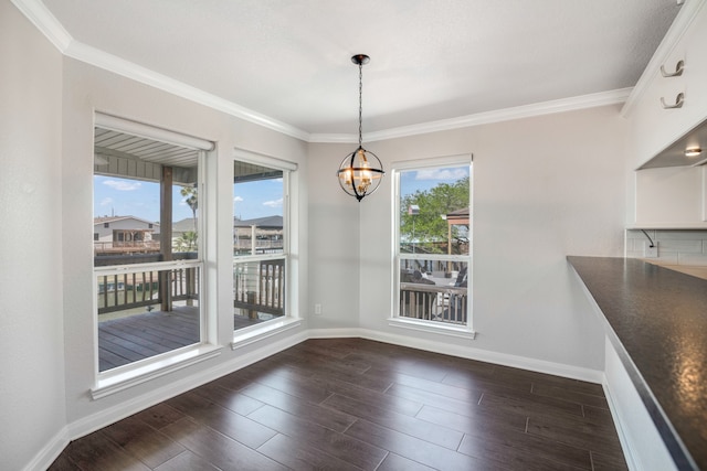 unfurnished dining area featuring dark hardwood / wood-style flooring, an inviting chandelier, and ornamental molding