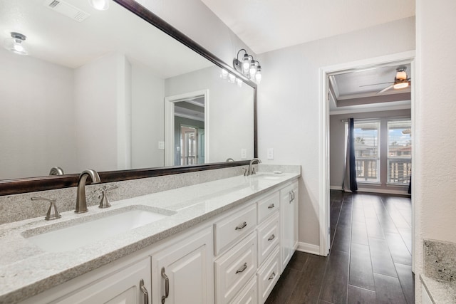 bathroom featuring wood-type flooring, double vanity, ceiling fan, and a raised ceiling