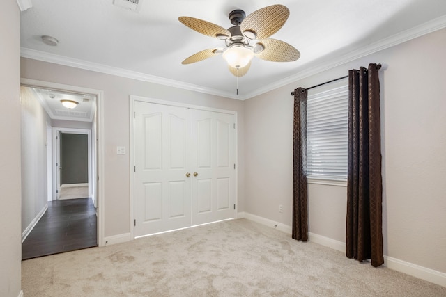 unfurnished bedroom featuring a closet, ceiling fan, crown molding, and carpet flooring