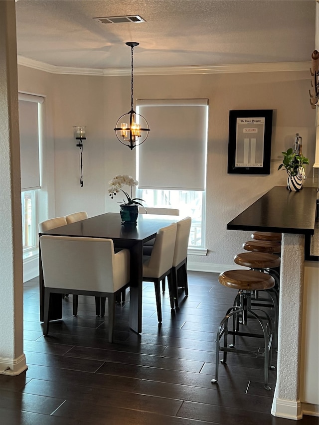 dining space with a chandelier, a healthy amount of sunlight, dark wood-type flooring, and crown molding