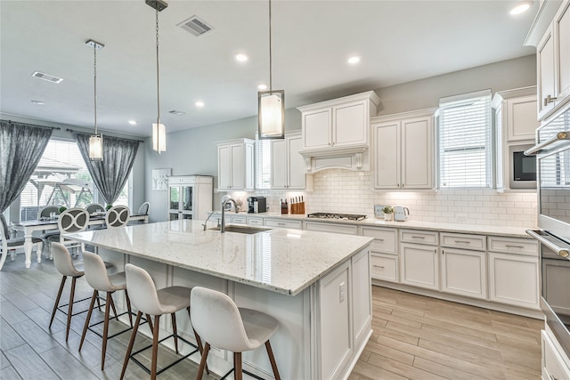 kitchen with tasteful backsplash, a center island with sink, decorative light fixtures, and appliances with stainless steel finishes