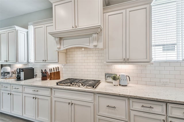 kitchen featuring white cabinetry, backsplash, plenty of natural light, and light stone counters