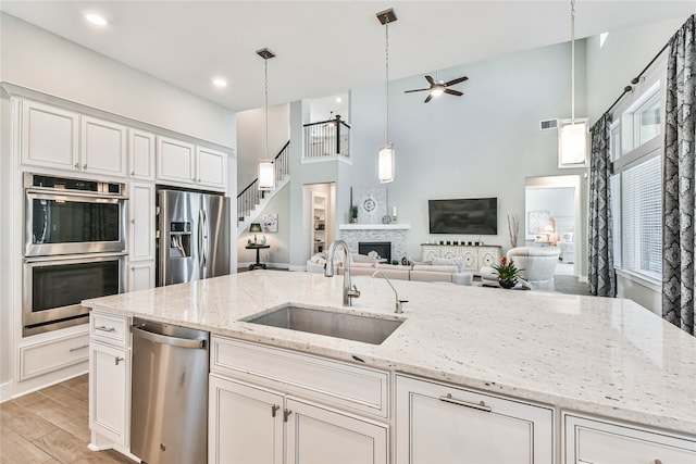 kitchen with hanging light fixtures, ceiling fan, appliances with stainless steel finishes, and light stone countertops