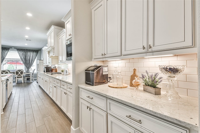 kitchen with white cabinets, tasteful backsplash, light stone countertops, and stainless steel appliances