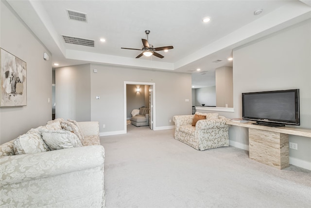 carpeted living room featuring ceiling fan and a raised ceiling