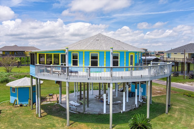 back of property with a wooden deck, a patio area, and a lawn