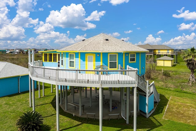 rear view of property featuring a yard, a deck, and a patio