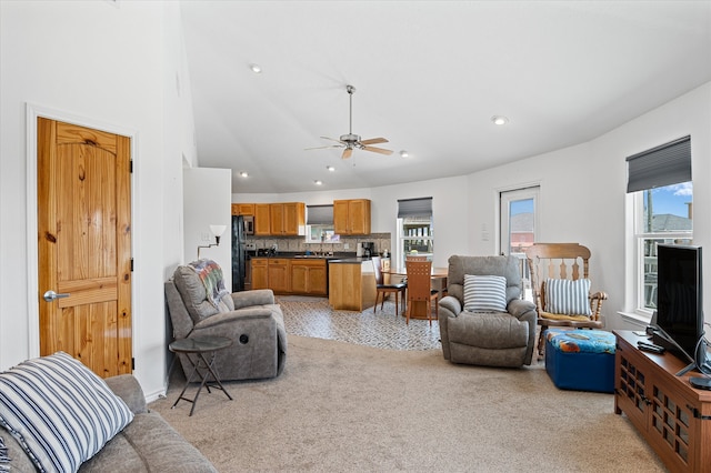 living room featuring ceiling fan, light colored carpet, and a high ceiling