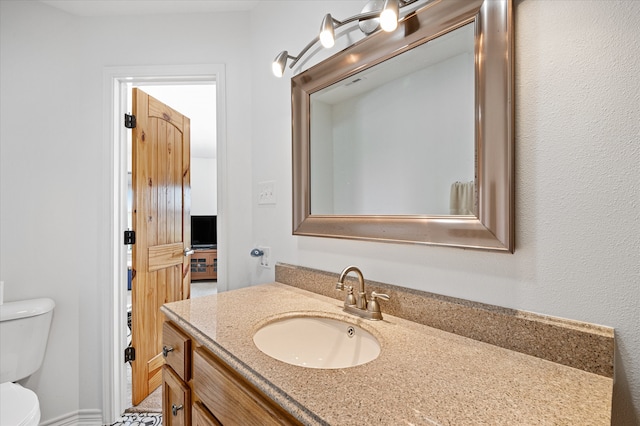 bathroom with toilet and vanity with extensive cabinet space