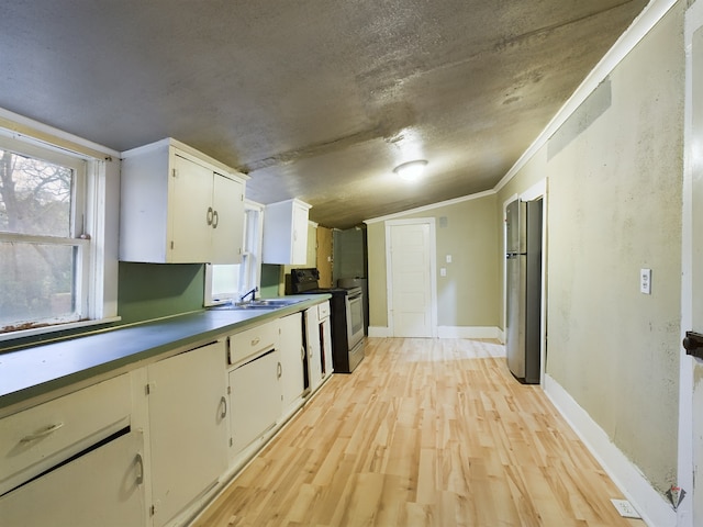 kitchen with vaulted ceiling, stainless steel appliances, white cabinetry, and light hardwood / wood-style floors