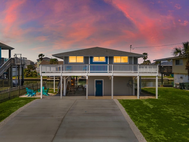 view of front of house with a deck, a lawn, and a patio